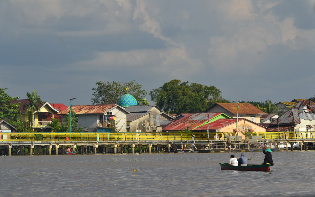 People in a small boat on the Kapuas River beside a West Borneo waterfront