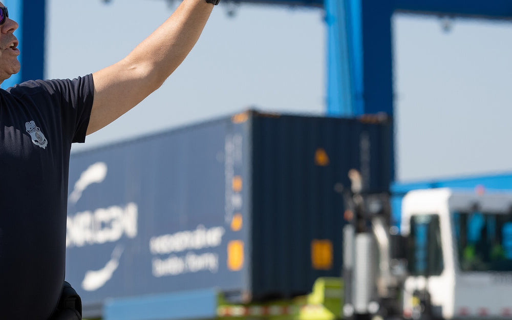 Cargo officer directing container equipment during a port inspection operation