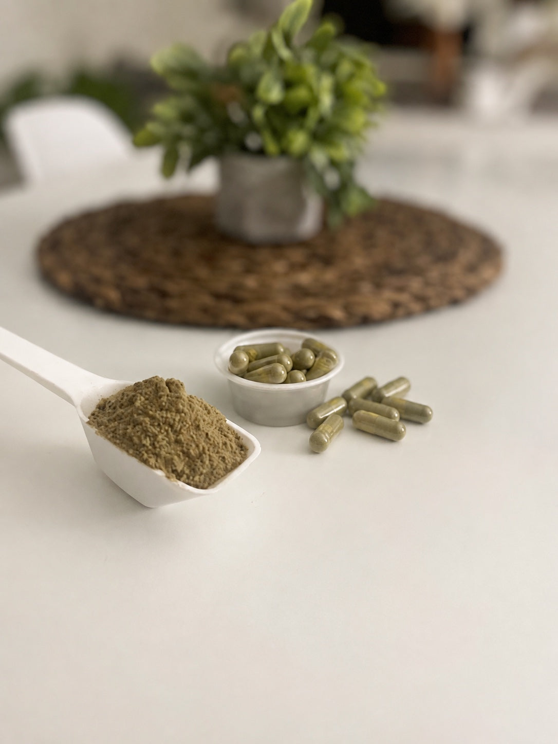 Kratom powder in a white scoop beside kratom capsules