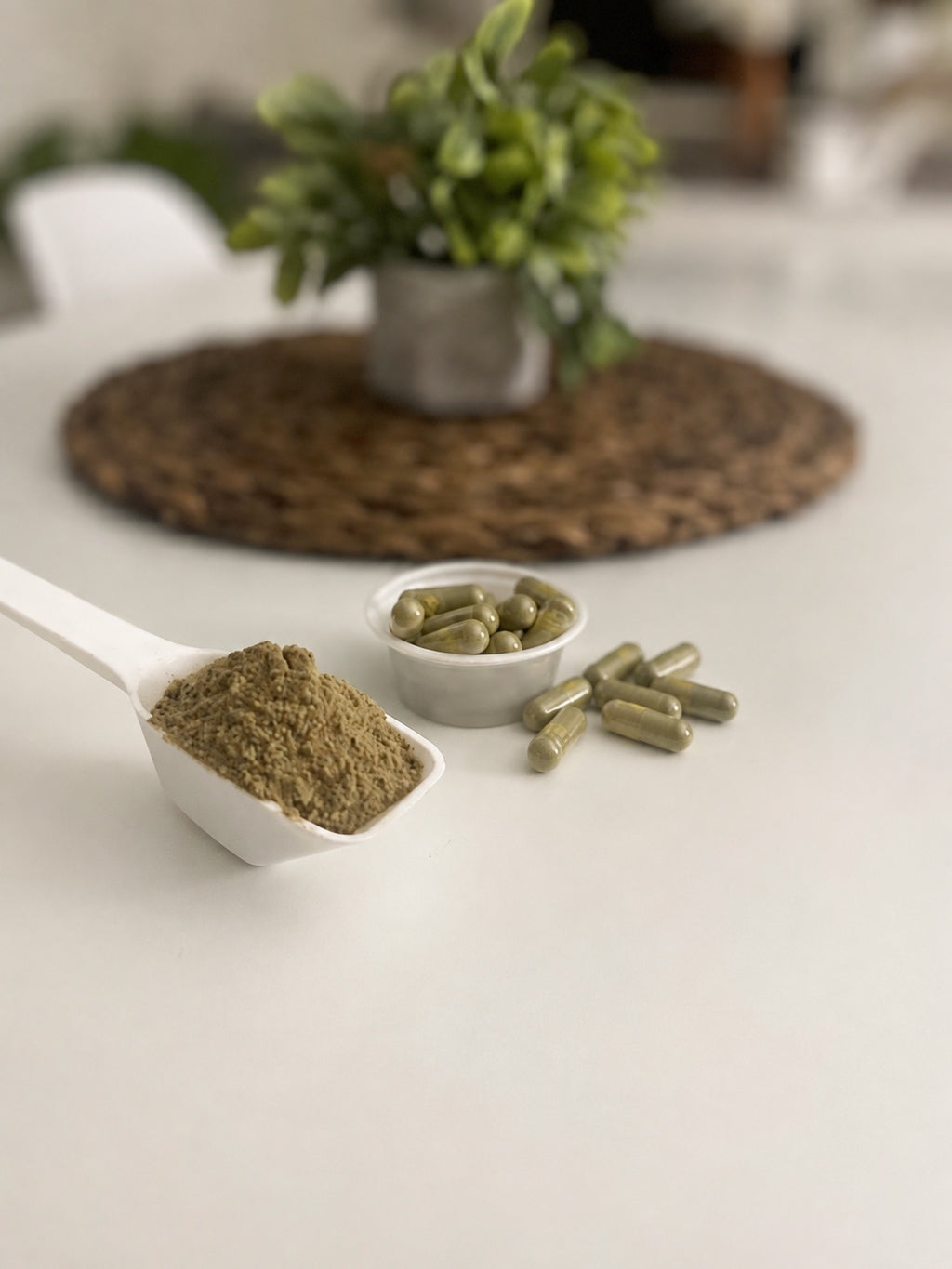 Kratom powder in a white scoop beside kratom capsules